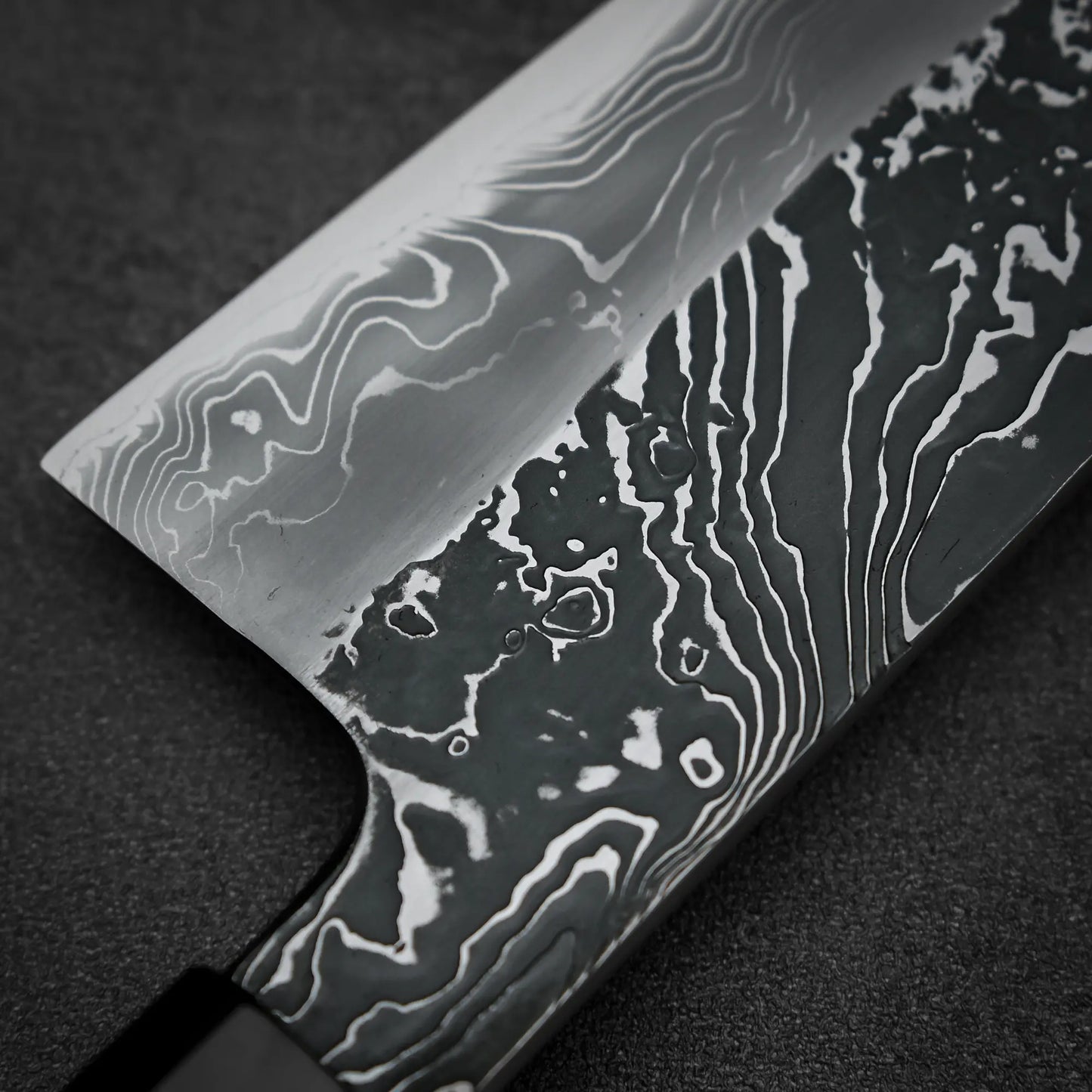 Macro shot of the back side of Yoshihide Masuda shirogami#2 kurouchi damascus tall gyuto knife