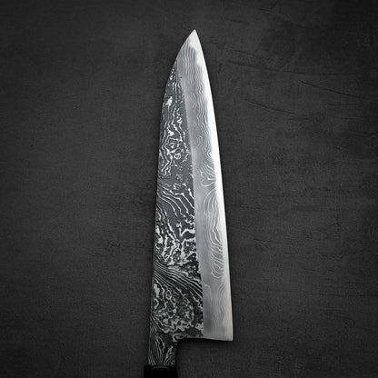 Close up view of the front blade of Yoshihide Masuda shirogami#2 kurouchi damascus tall gyuto knife in vertical position