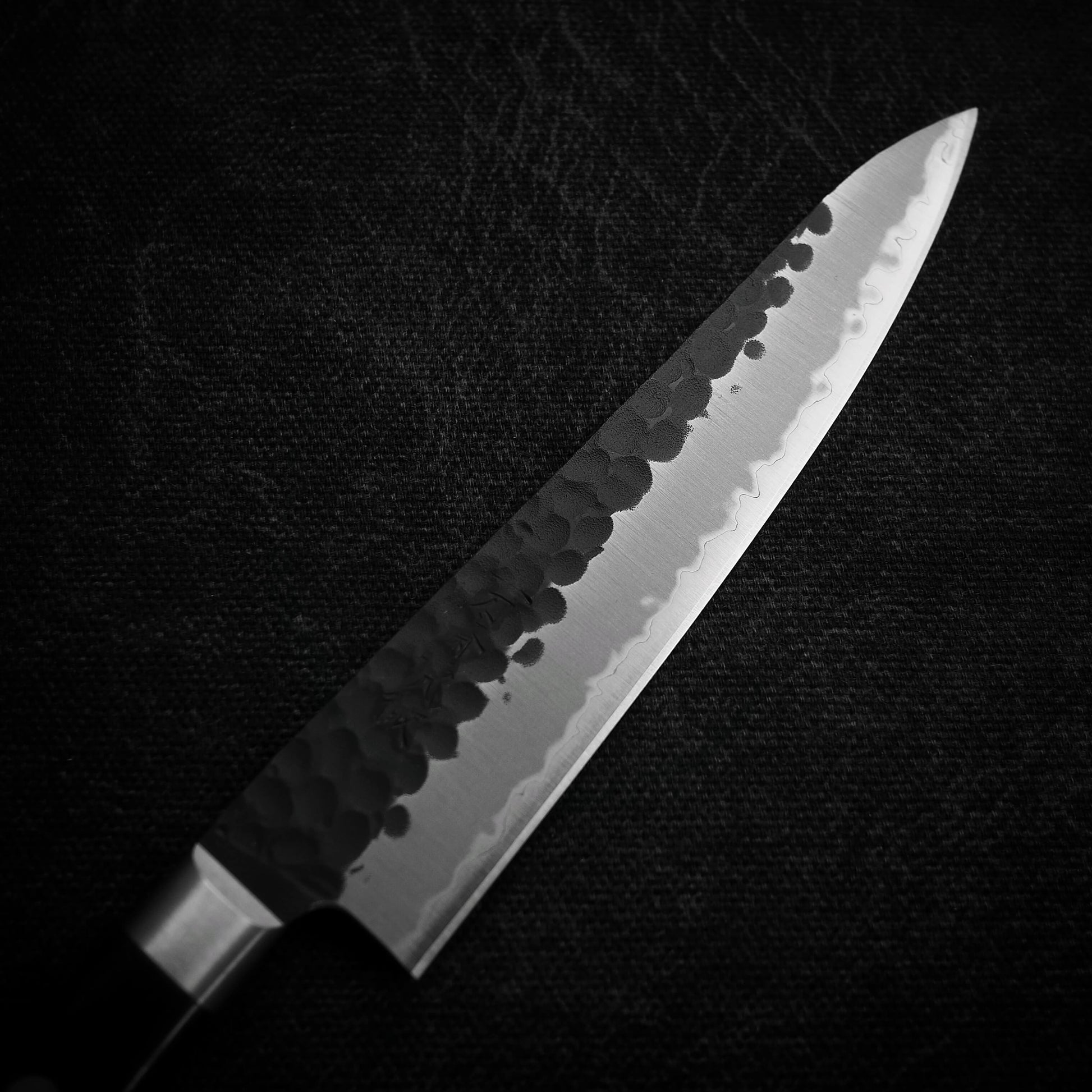 Top view of the blade of Ittosai Kotetsu tsuchime kurouchi aogami super petty knife. Image focuses on the right side of the blade
