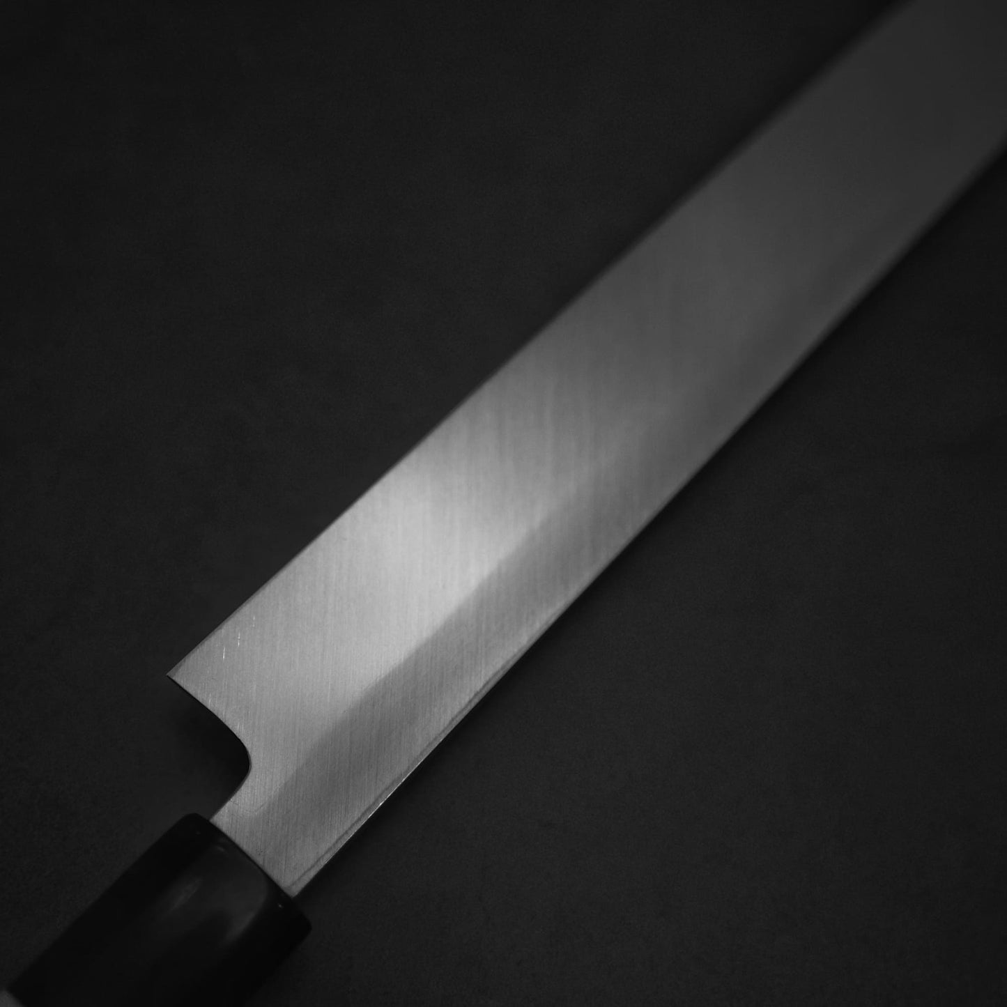 Close up view of Yoshihiro josaku shirogami #2 kiritsuke yanagiba 300mm. Image focuses on the back side of the knife showing the urasuki