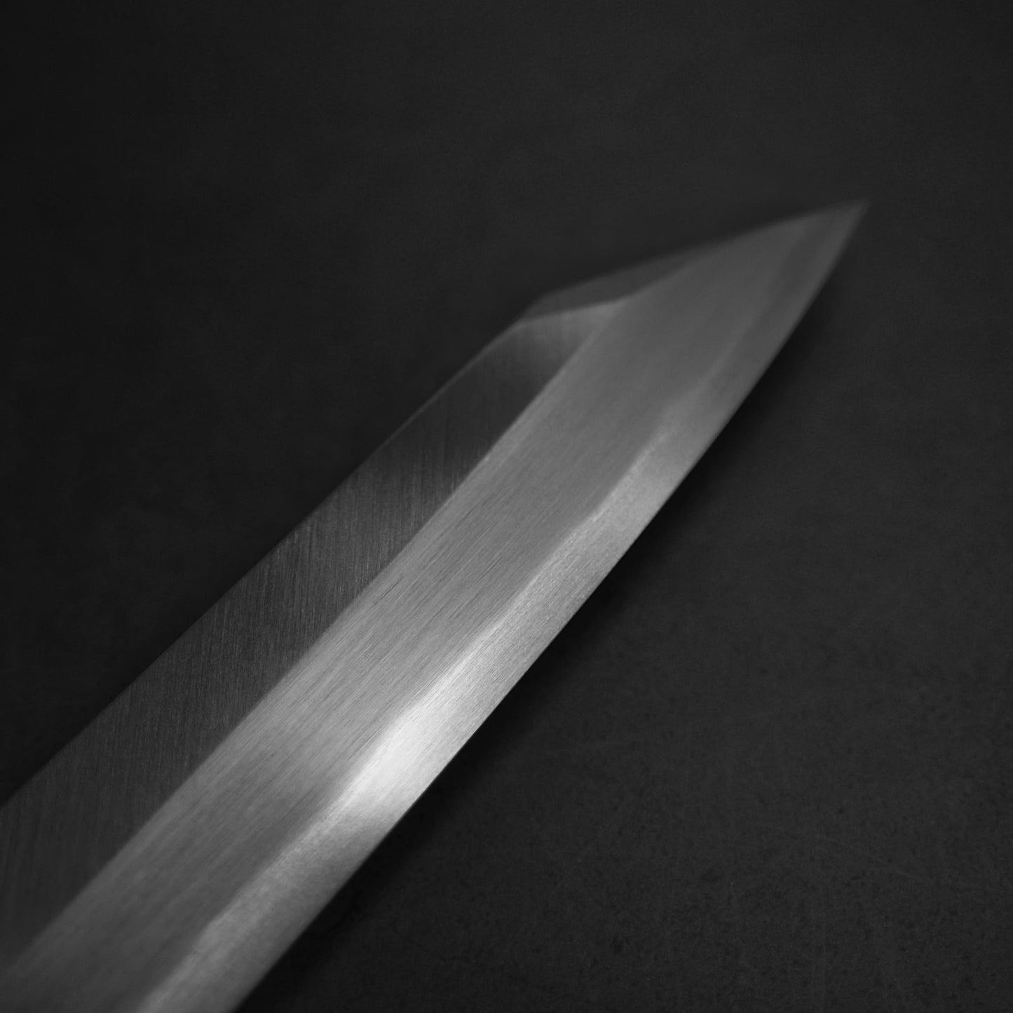 Close up view of Yoshihiro josaku shirogami #2 kiritsuke yanagiba 300mm. Image focuses on the tip area of the right side of the blade