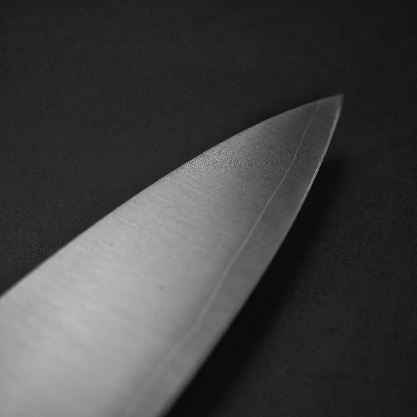 Close up view of Sukenari HAP40 240mm gyuto. Image focuses on the tip area of the right side of the blade